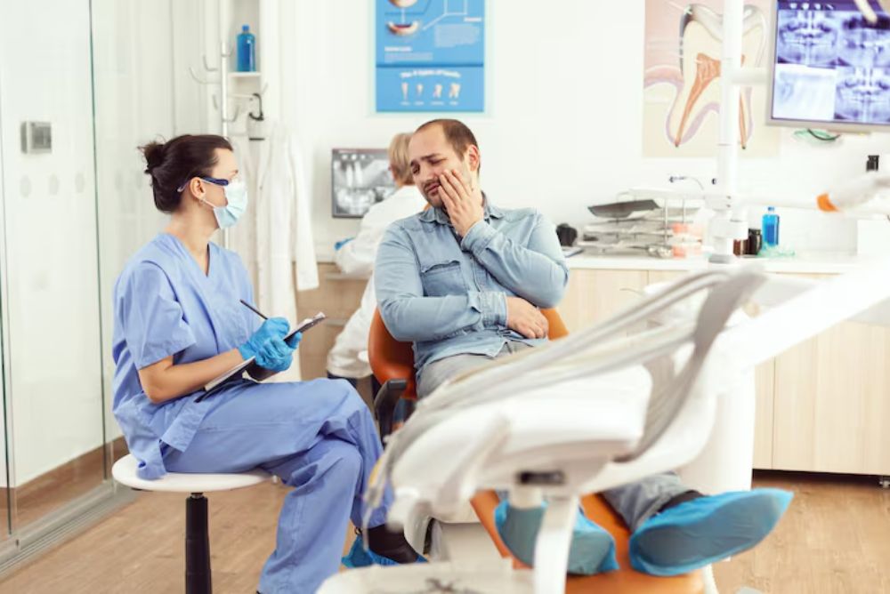 man with tooth pain speaking to a dental professional about emergency dental care